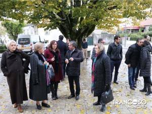 Grupo de pessoas reunidas numa praça junto a uma árvore de grandes dimensões durante uma visita oficial.