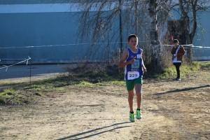 Jovem corredor com dorsal número 229 em prova de corrida, em terreno junto a um rio com barragem ao fundo.