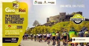 Grupo de ciclistas em vestuário colorido pedalam numa estrada com castelo medieval ao fundo, sob céu parcialmente nublado.