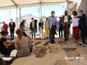 Autoridades e visitantes observam trabalho de escavação arqueológica sob tenda em sítio histórico.
