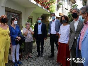 Grupo de oito pessoas em visita oficial numa rua de Trancoso, com arquitetura tradicional ao fundo e vegetação pendente.